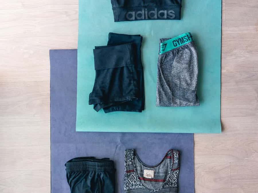 Folded workout clothes laid out on two exercise mats on a wooden floor.
