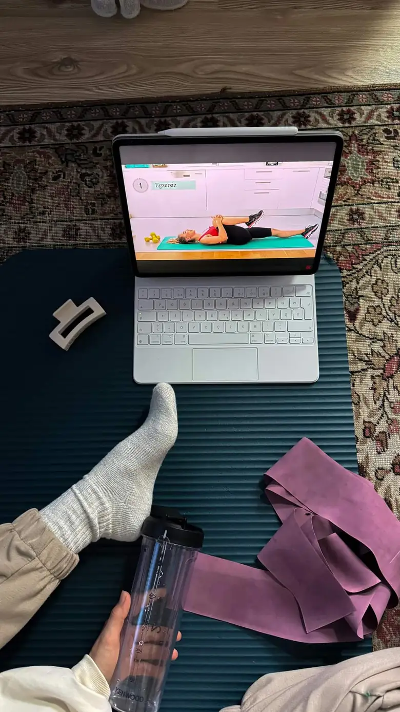 Home workout setup with mat, bands, laptop, and water bottle