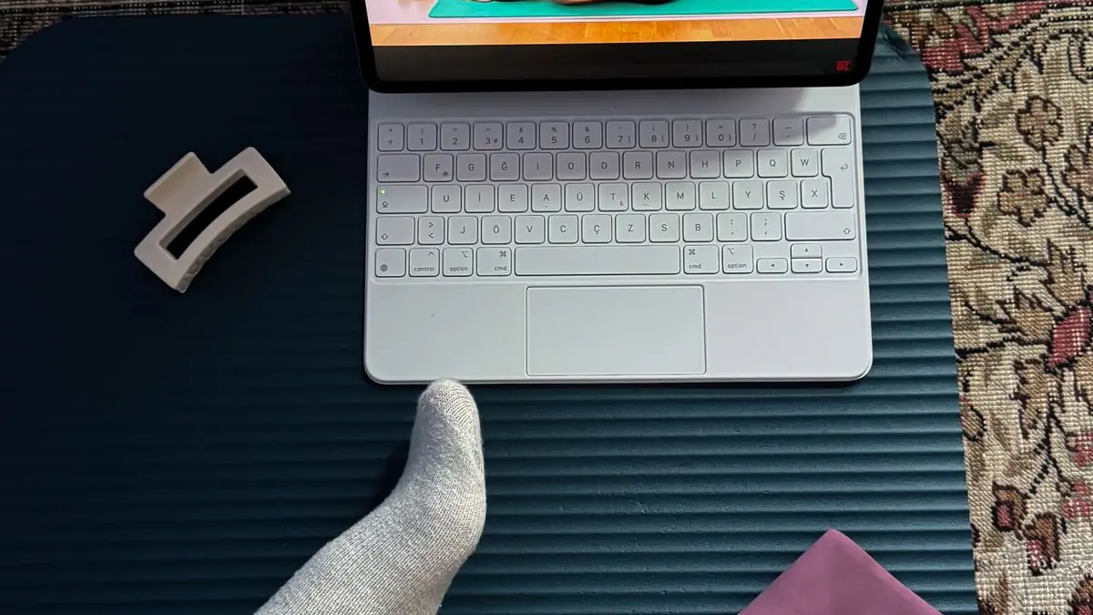 First-person view down at a home exercise mat, with a tablet playing a guided workout and a resistance band beside it.